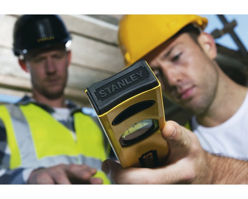 Doi muncitori în construcții cu un instrument de nivelă cu bulă de aer marca Stanley.