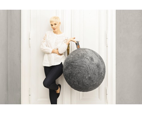 Puf decorativ în formă de bilă lângă o femeie lângă o ușă