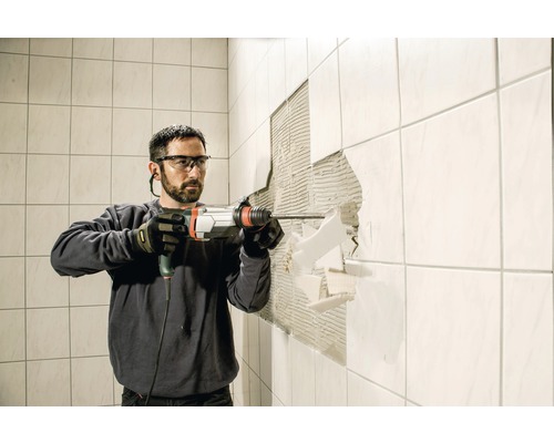Bărbat care îndepărtează plăcile cu un ciocan rotopercutor