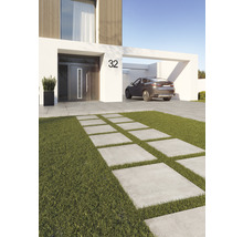Aspect modern al casei cu o cărare din plăci de beton printr-o zonă cu gazon și o mașină în carport