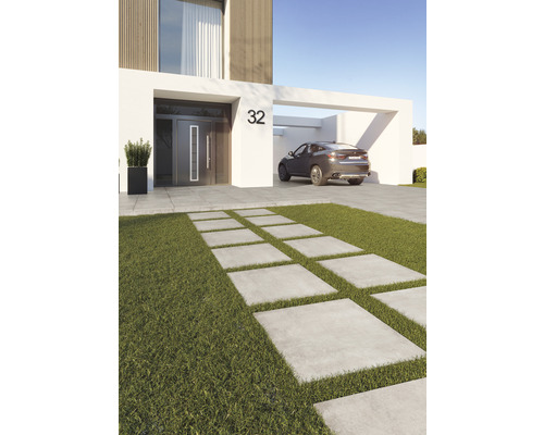 Aspect modern al casei cu o cărare din plăci de beton printr-o zonă cu gazon și o mașină în carport