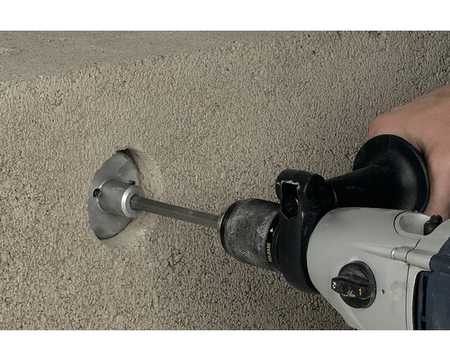 O mașină de găurit face o gaură într-un perete de beton.