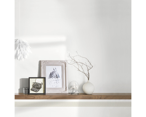 Bordură decorativă în cameră cu rame foto, vază și lampă.