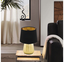 Lampă de masă decorativă cu abajur negru și bază aurie pe o măsuță laterală
