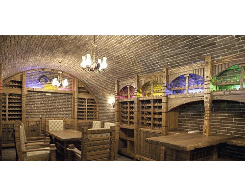 Cameră de vinuri cu rafturi din lemn, boltă de cărămidă și mese