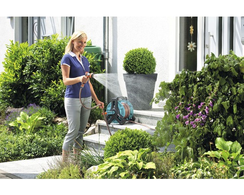 Femeie udând grădina cu o rolă de furtun