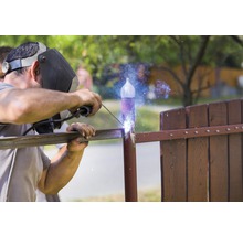 Un sudor sudează o balustradă metalică afară.