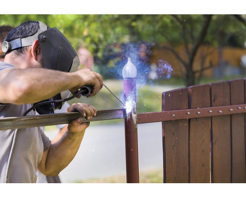 Un sudor sudează o balustradă metalică afară.