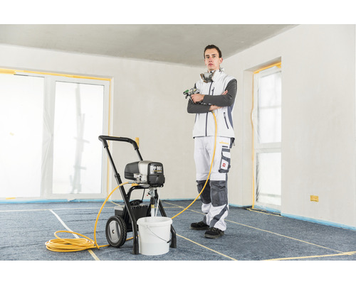 Bărbat cu un pulverizator de vopsea într-o cameră.