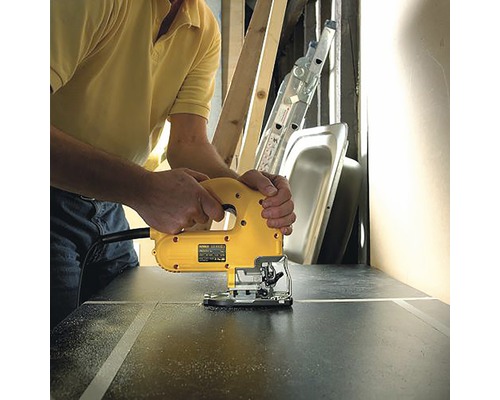 Un bărbat taie o piesă de lucru cu un ferăstrău vertical