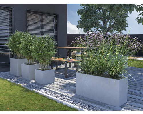 Zonă de grădină cu jardiniere din beton, plante și zonă de relaxare pe terasă