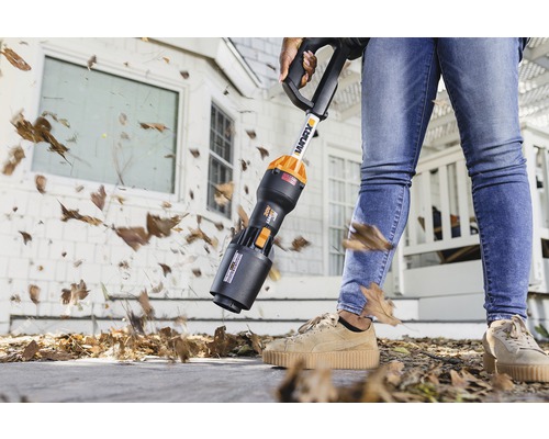 Aspirator de frunze cu acumulator în uz pentru îndepărtarea frunzelor din fața unei case.