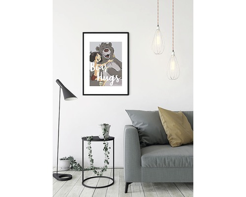 Cameră de zi decorativă cu o imagine înrămată a lui Mowgli și Baloo cu inscripția îmbrățișări de urs, o lampă de podea, o masă și o canapea.