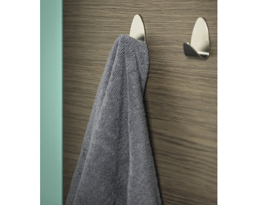 Prosop pe un cârlig adeziv argintiu pe un perete din lemn