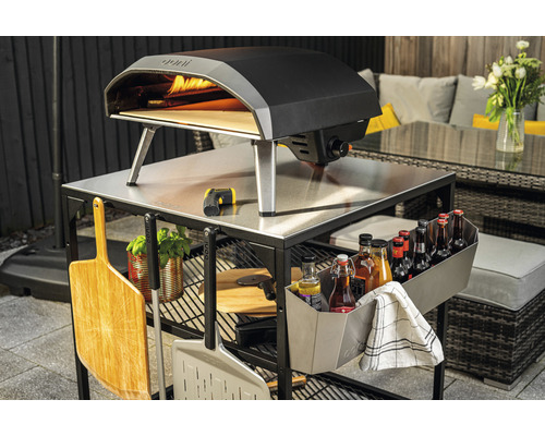 Cuptor de pizza Ooni pe un cărucior de bucătărie exterioară cu accesorii în grădină.