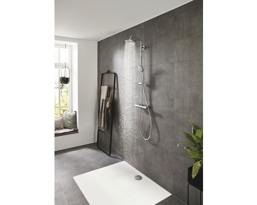 Baie modernă cu duș tip ploaie și duș de mână în fața unei faianțe gri.