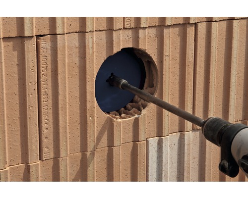 Mașină de găurit care face o gaură într-un perete de cărămidă