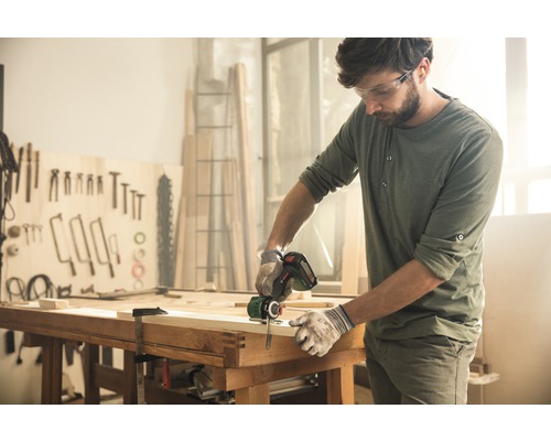 Artizan taie lemn cu un fierăstrău electric tip sabie într-un atelier.