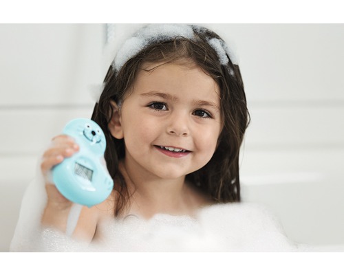 Fetiță cu spumă de baie care ține un termometru de baie în formă de focă