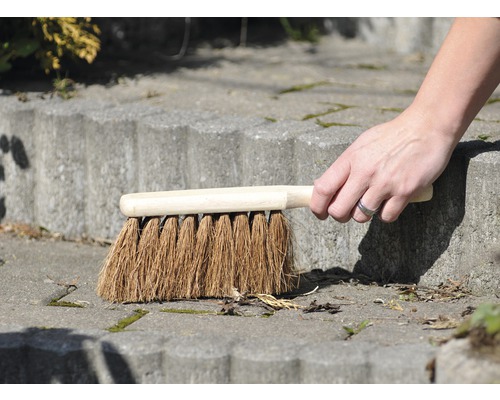 O mână mătură o scară de piatră cu o perie