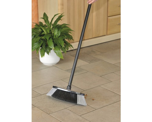 O mătură cu coadă este folosită pe o podea cu gresie.