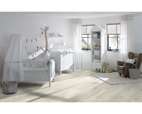 Cameră luminoasă pentru copii cu pătuț, masă de înfășat, bibliotecă și fotoliu pe podea de lemn deschisă la culoare