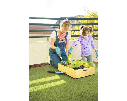 Mamă și fiică grădinăresc împreună într-o jardinieră înaltă pe un balcon