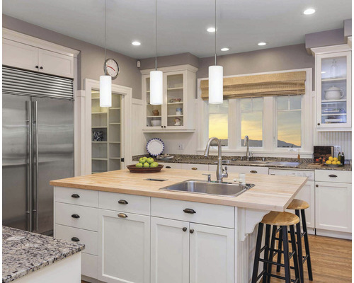 Bucătărie luminoasă cu insulă de bucătărie, chiuvetă, robinet și locuri pentru stat jos.