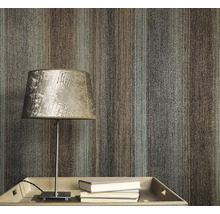 Prim-plan al unui perete cu tapet cu model în dungi, o masă cu o lampă și cărți