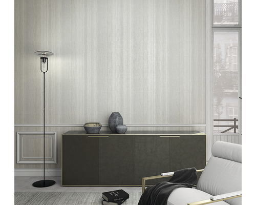 Cameră de zi cu lampă de podea, comodă și fotoliu în fața unui tapet cu dungi