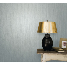 Prim-plan al unui perete cu tapet texturat lângă o masă cu lampă