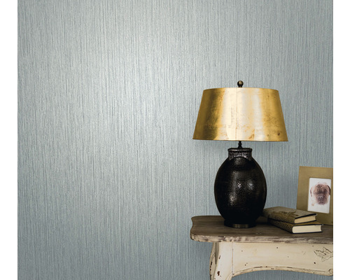 Prim-plan al unui perete cu tapet texturat lângă o masă cu lampă