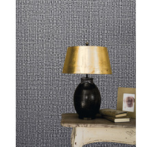 Prim-plan cu tapet cu model, cu o noptieră, o lampă, cărți și o ramă foto.