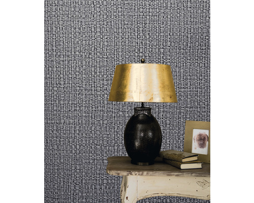 Prim-plan cu tapet cu model, cu o noptieră, o lampă, cărți și o ramă foto.