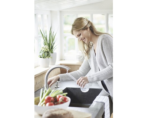 Femeie spălând legume într-o chiuvetă de bucătărie cu robinet.