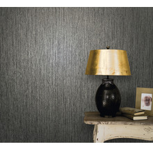 Prim-plan al unui perete cu tapet texturat, o masă și o lampă de masă.