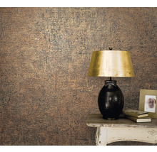 Prim-plan cu un perete cu tapet texturat lângă o masă cu o lampă, cărți și o ramă foto.