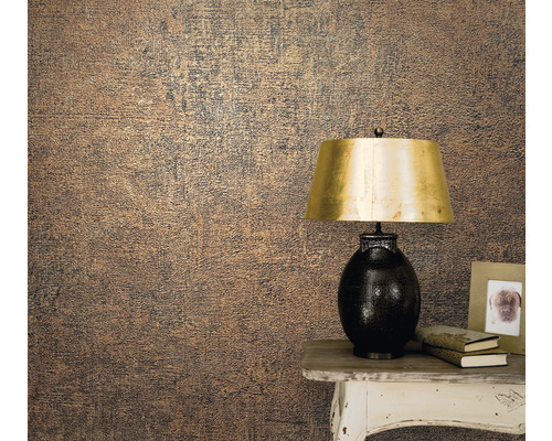 Prim-plan cu un perete cu tapet texturat lângă o masă cu o lampă, cărți și o ramă foto.