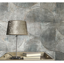 Prim-plan cu un perete gri al camerei cu un model de tapet circular, o masă cu o lampă și cărți.