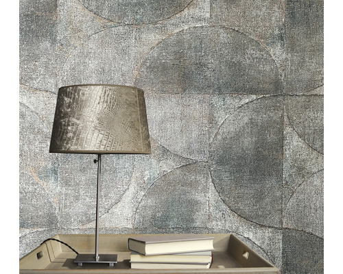 Prim-plan cu un perete gri al camerei cu un model de tapet circular, o masă cu o lampă și cărți.