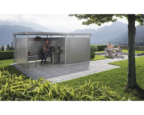 Loc de grătar acoperit cu un bărbat care face grătar și familie în fundal