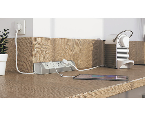 Priză multiplă cu telefon mobil și aparat de cafea conectate pe un blat de lucru