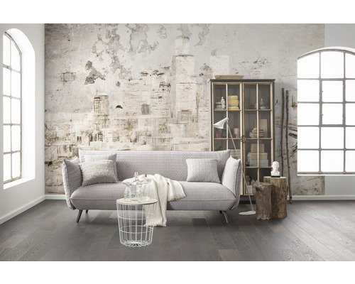 Cameră de zi cu canapea, raft, masă și decor în fața unui perete cu model de ziar