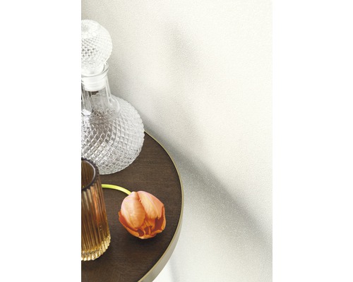 Tapetă decorativă pe un perete lângă o masă cu carafă și floare.