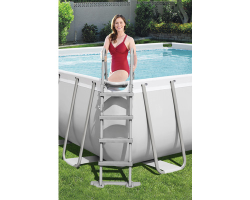 Femeie urcând pe o scară într-o piscină dreptunghiulară cu cadru
