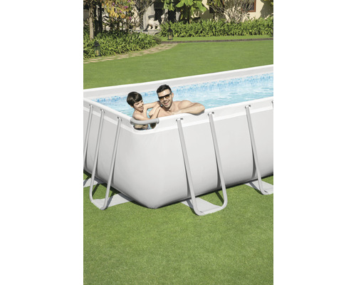 Piscină dreptunghiulară cu cadru din oțel în grădină cu doi oameni în apă