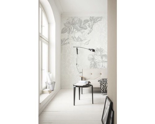 Cameră luminoasă cu tapet floral, lampă și loc de ședere