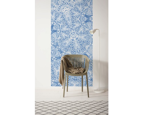 Cameră cu tapet cu model, un scaun, o pătură, o lampă de podea și un covor