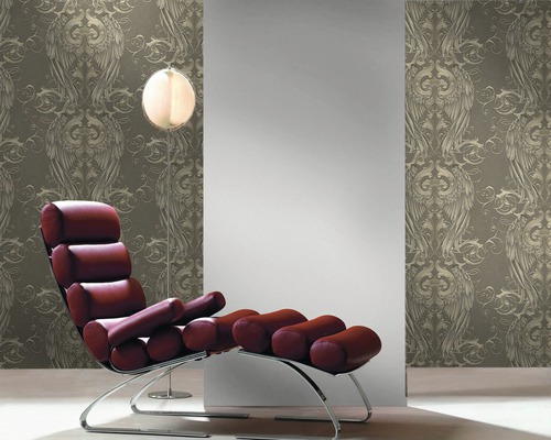 Tapetă decorativă cu model ornamental înaripat într-un interior cu fotoliu și lampadar.