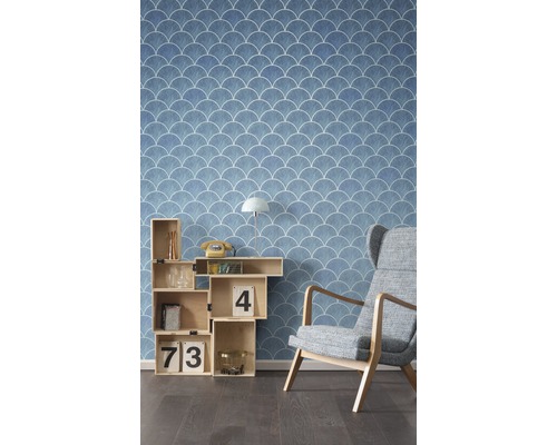 Vedere a unei camere cu tapet albastru cu model de scoici, raft cubic și fotoliu